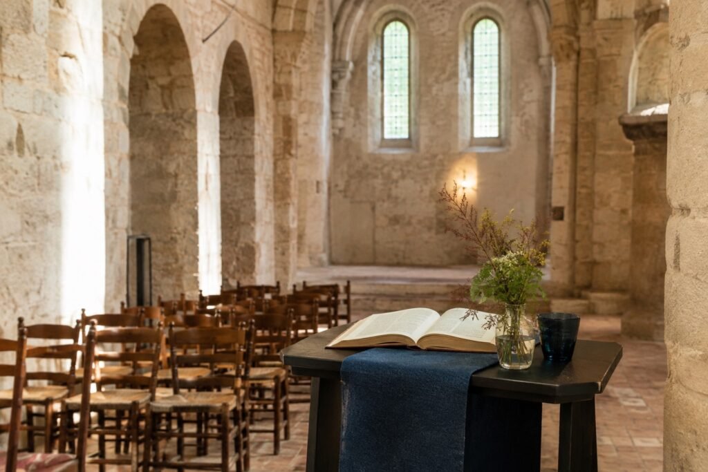 Lege lezingopstelling met houten stoelen, lessenaar en open boek in een rustige abdijkerk