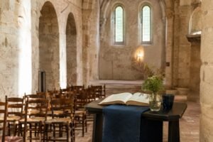 Lege lezingopstelling met houten stoelen, lessenaar en open boek in een rustige abdijkerk