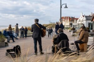 Straatmuzikanten spelen gitaar, accordeon en percussie bij de kust van Egmond aan Zee
