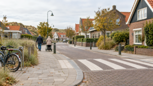 Voetgangers lopen over een toegankelijk trottoir bij een oversteekplaats in een kustdorp